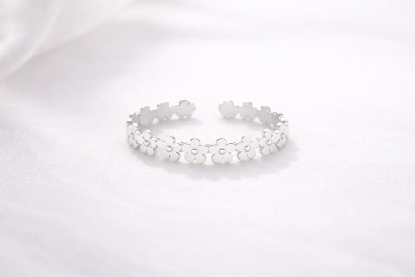 Bracelet argenté ouvert orné de fleurs stylisées sur fond blanc