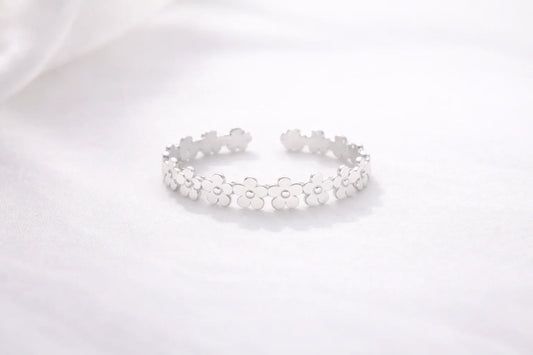 Bracelet argenté ouvert orné de fleurs stylisées sur fond blanc