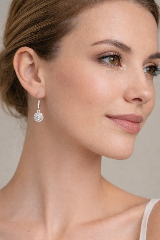 Femme portant une boucle d'oreille argentée en forme de boule tressée, visage en gros plan