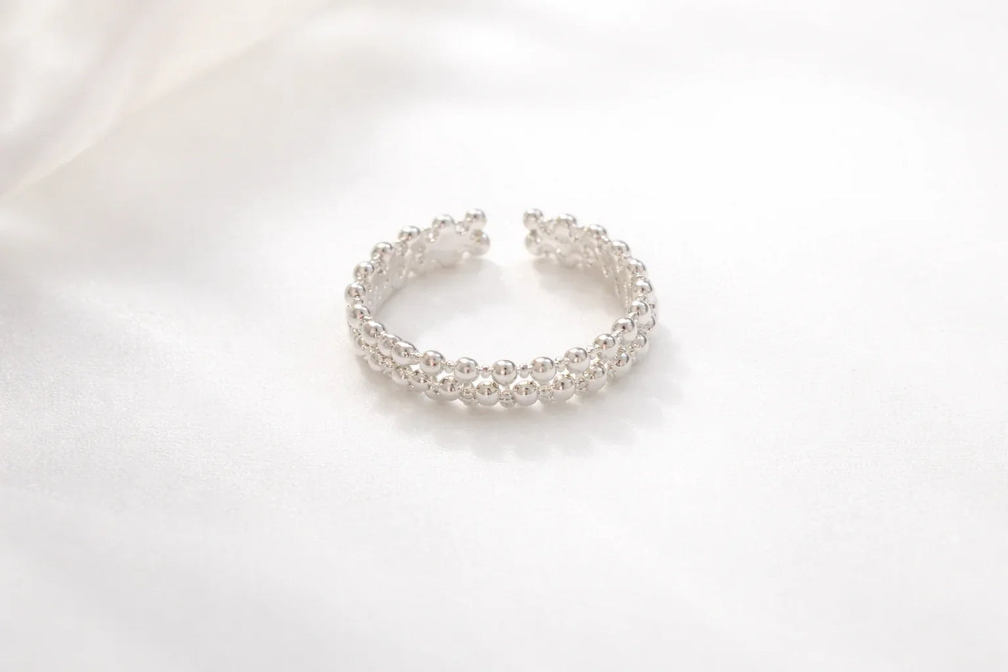 Bague argentée composée de deux rangées de boules brillantes sur fond blanc