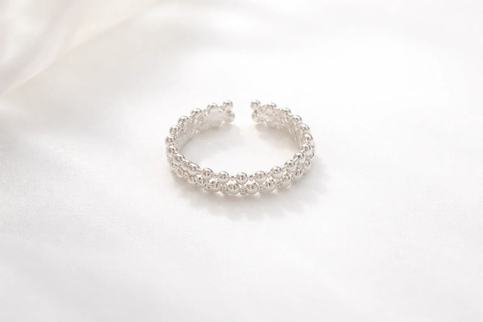 Bague argentée composée de deux rangées de boules brillantes sur fond blanc