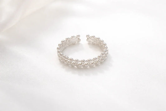 Bague argentée composée de deux rangées de boules brillantes sur fond blanc