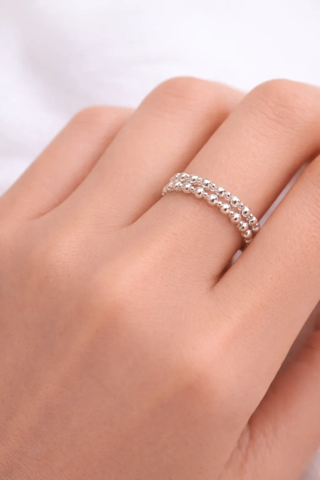 Bague argent à deux rangs de perles brillantes portée sur un doigt