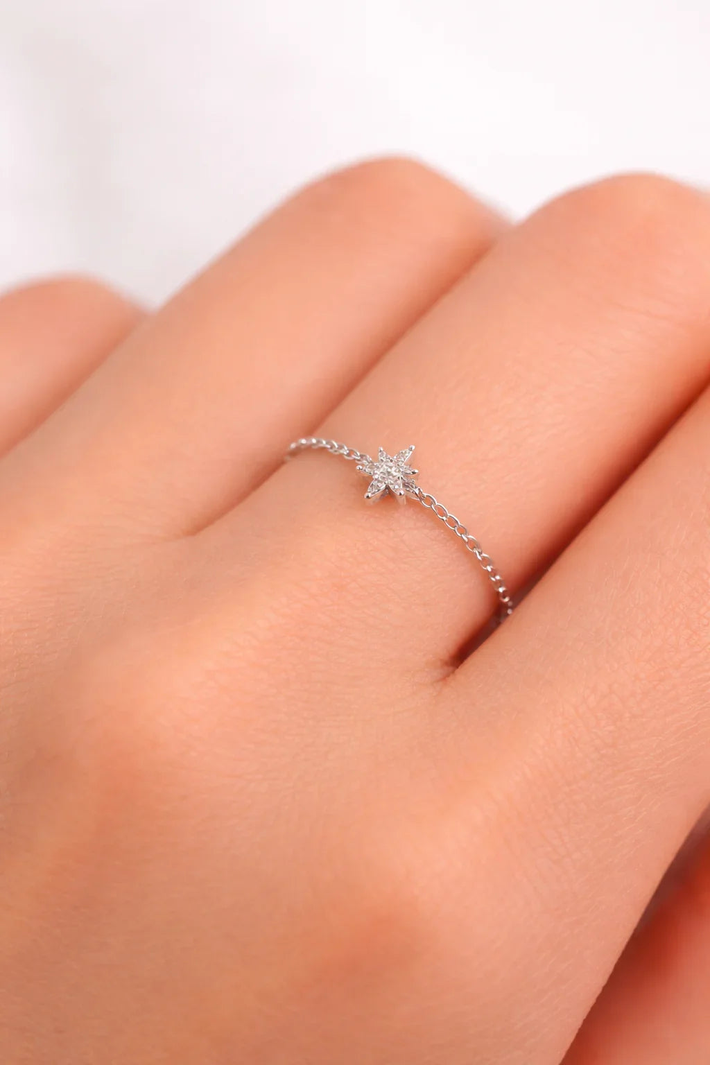 Bague fine en argent ornée d'une petite étoile sertie de pierres brillantes portée sur un doigt
