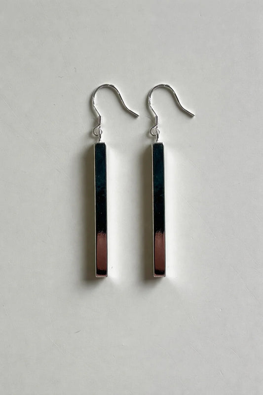 Boucles d'oreilles pendantes en métal argenté avec barre rectangulaire brillante sur fond blanc