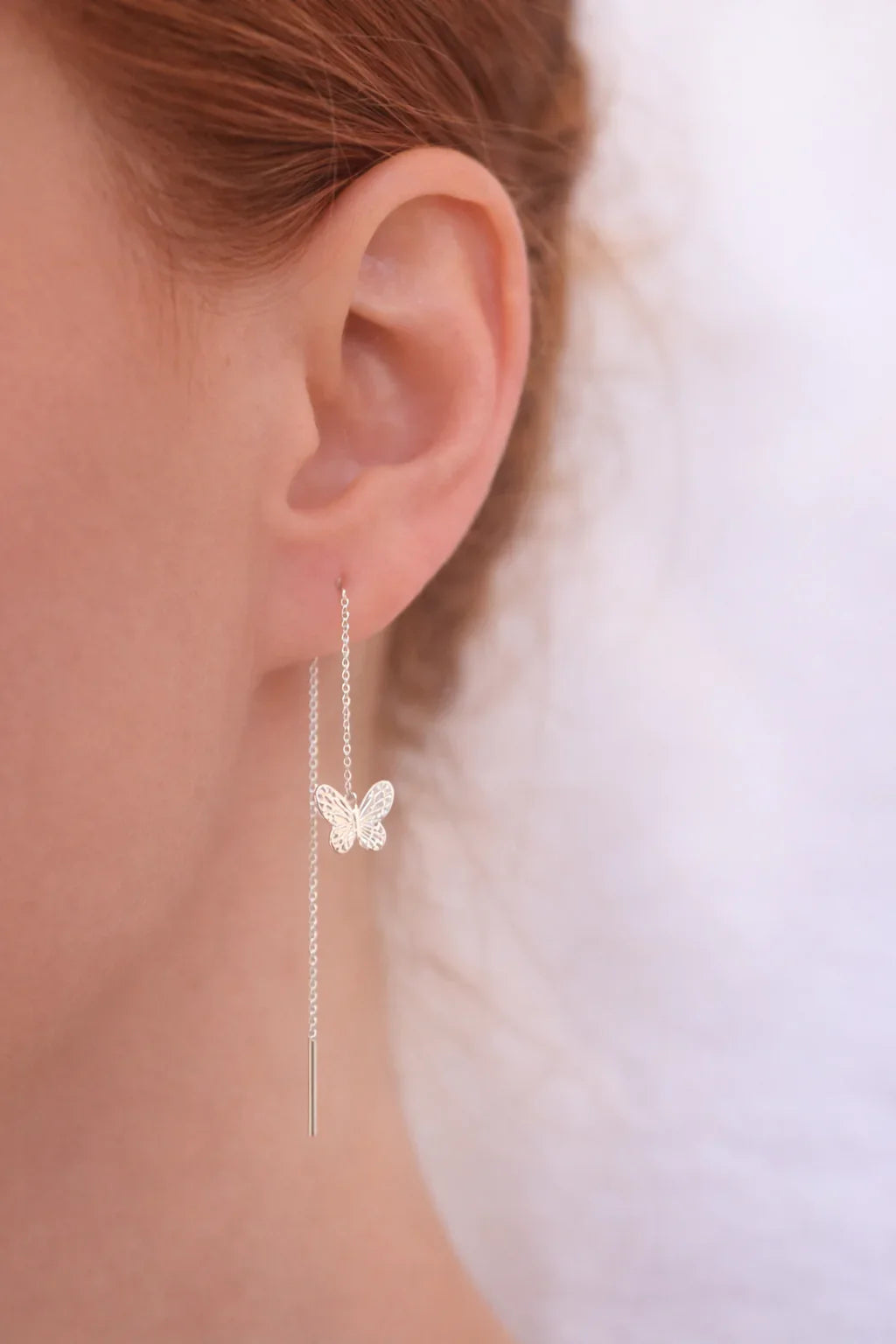 Femme élégante portant une boucle d'oreille papillon en argent pur suspendue