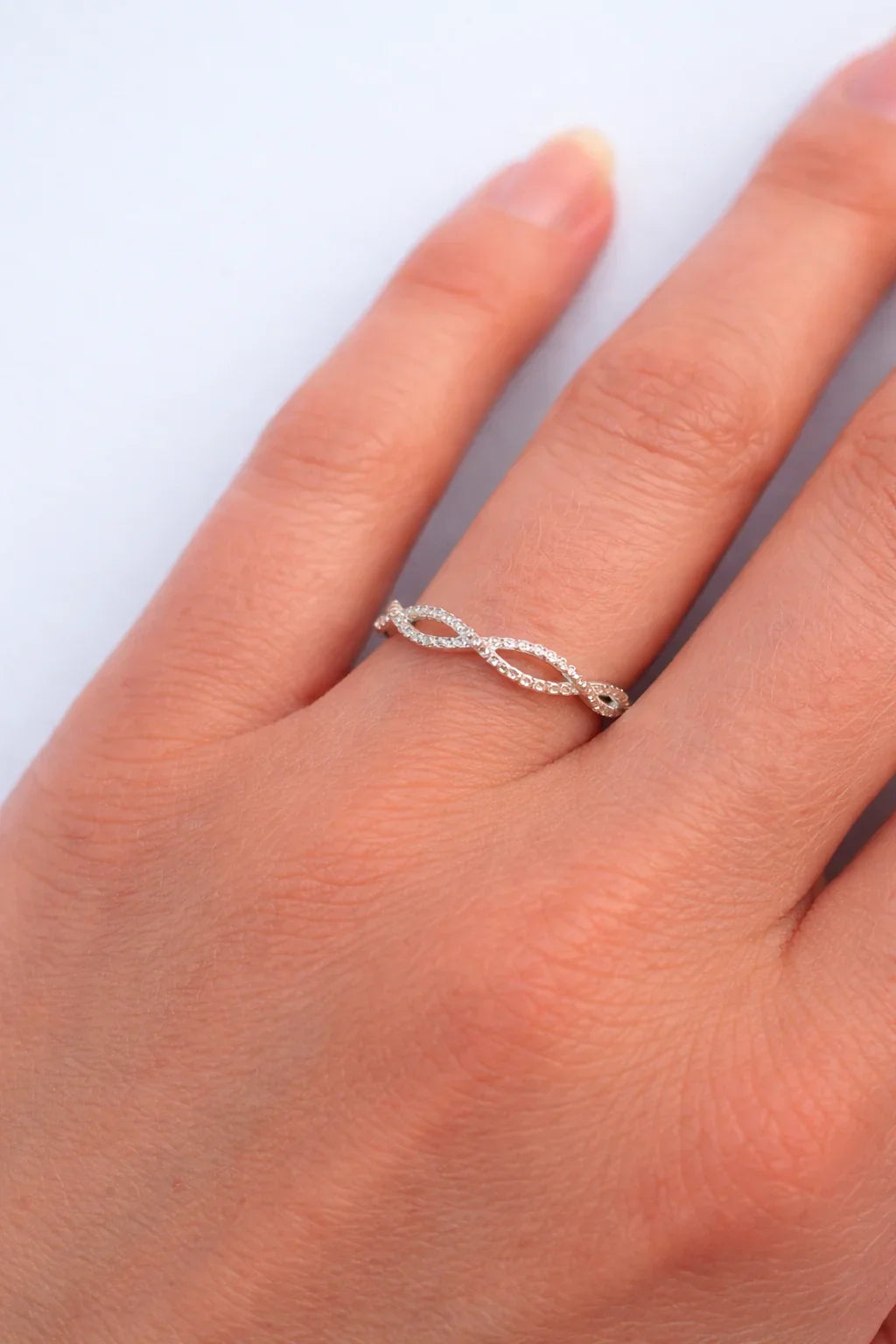 Bague fine torsadée en argent avec petits cristaux portée sur un doigt féminin