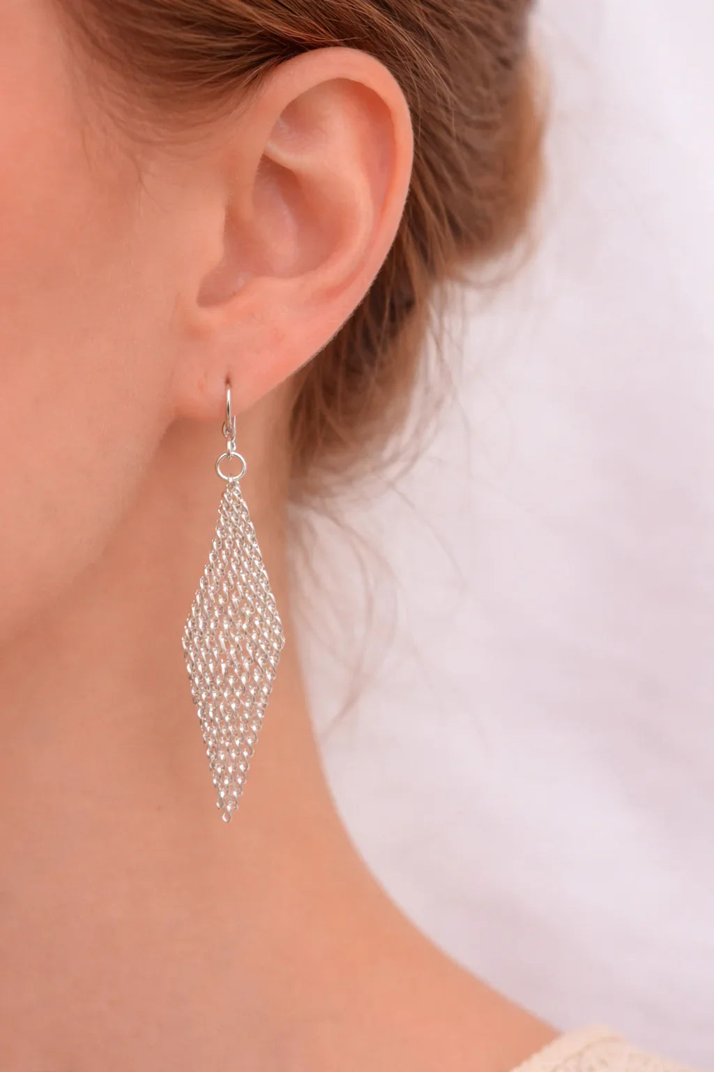 Femme élégante portant une boucle d'oreille en argent pur de forme triangulaire tressée